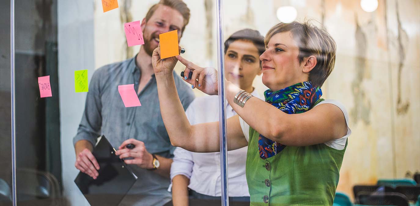 woman-writing-content-on-sticky-note-with-team